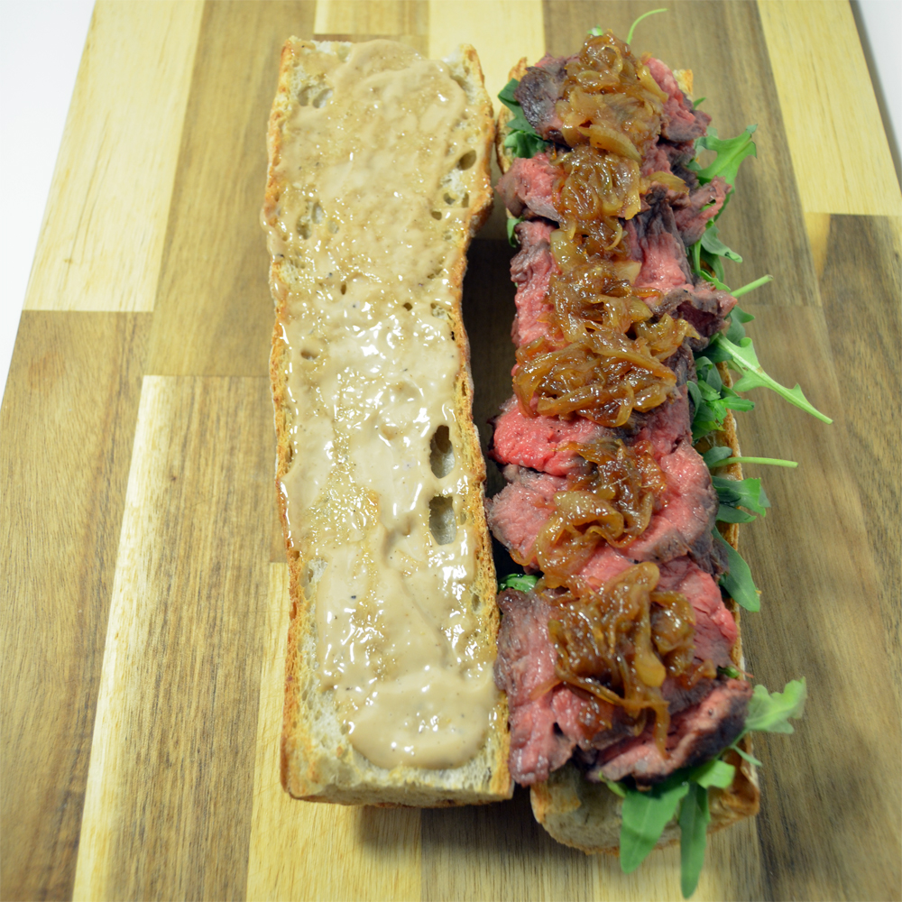 Steak sandwich with caramelized onions, arugula and mayo.