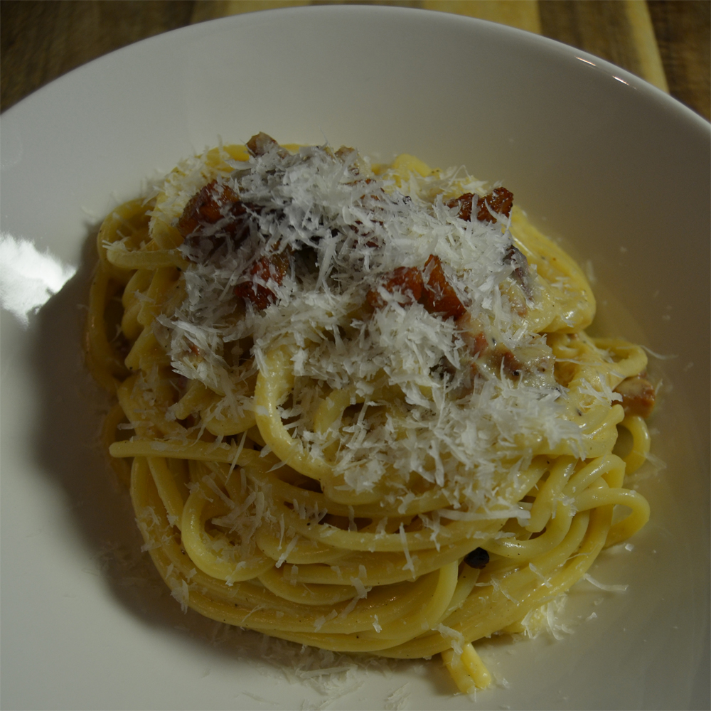 Spaghetti alla carbonara topped with grated pecorino romano.
