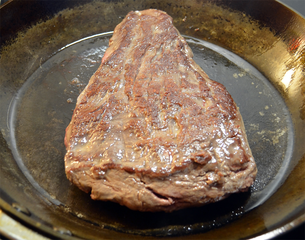 Fillet cap steak being cooked on a carbon steel skillet.